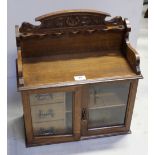 An Edwardian Arts and Crafts style oak smoker's cabinet with pipe rack gallery above twin glazed