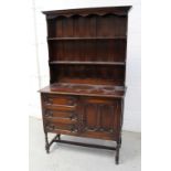 A 1920s oak dresser with boarded plate rack raised on barleytwist supports, width 107cm.