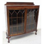 An early-to-mid 20th century mahogany bow-front two-door glazed bookcase on ball and claw feet,