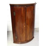 A George III mahogany bow-front corner cupboard,