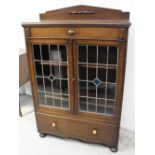 A 1930s oak floor standing bookcase with wooden galleried back above two stained and leaded glass