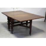 A Victorian mahogany drop leaf dining table raised on lobed baluster supports to castors,