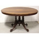 A Victorian walnut and inlaid loo table raised on carved quadripartite base to castors,