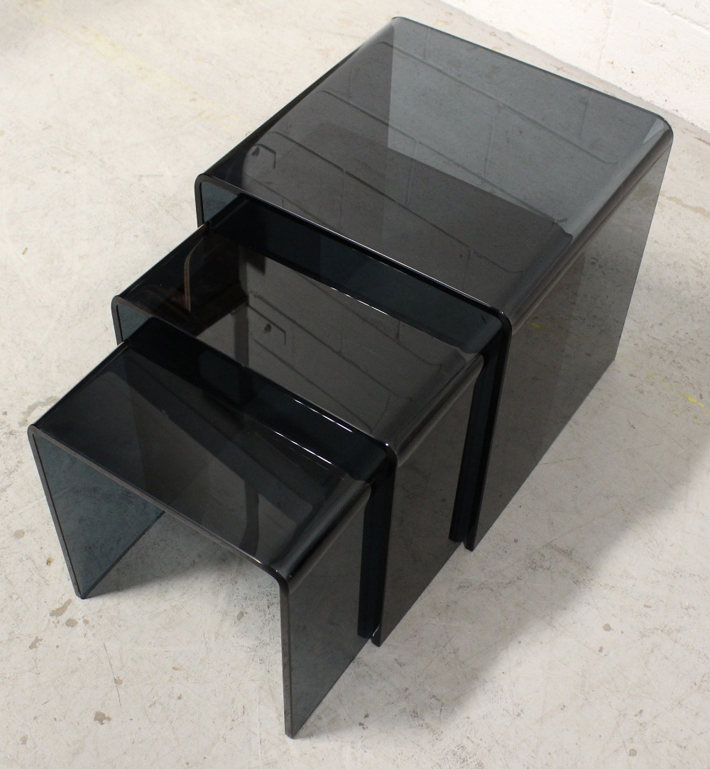 A nest of three late 20th century smoked glass tables, formed of a single sheet bent into a cube,