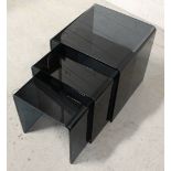 A nest of three late 20th century smoked glass tables, formed of a single sheet bent into a cube,