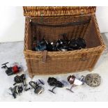 A large wicker fishing creel containing an assortment of course and fly fishing reels,