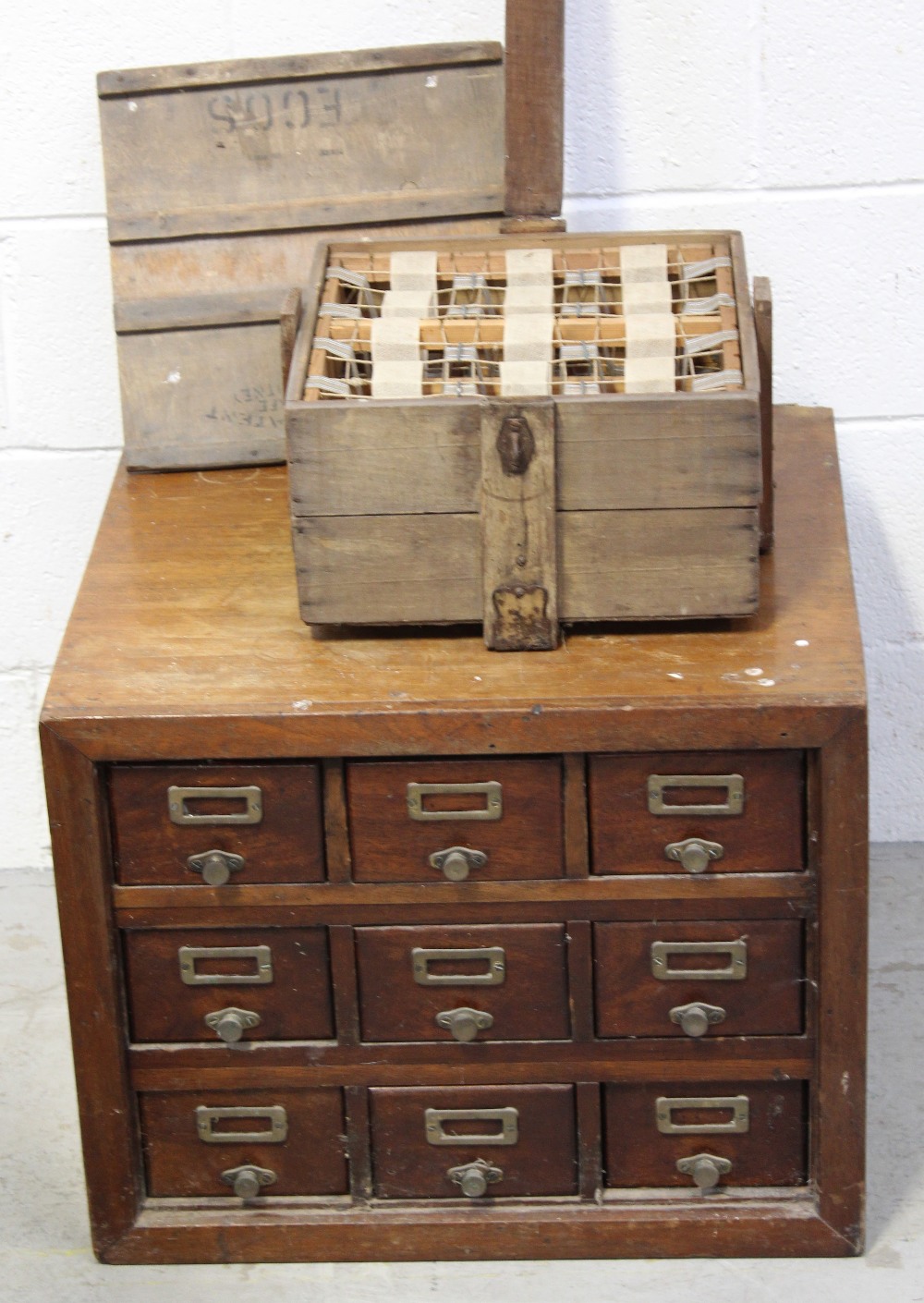 A vintage farm egg carrying box and an early 20th century mahogany filing cabinet with nine small