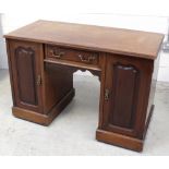 A late 19th early 20th century mahogany knee hole desk with frieze drawer flanked by cupboard doors,