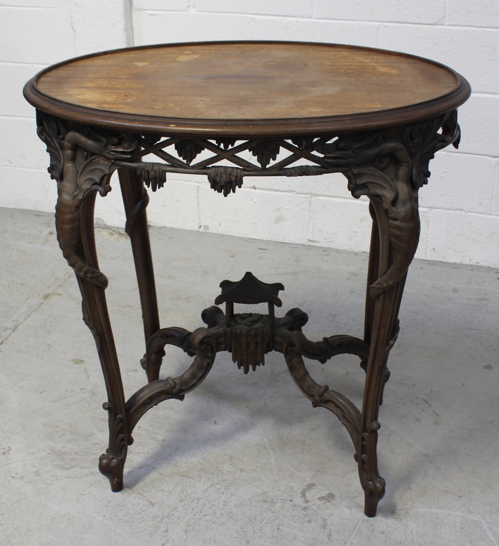 A late 19th/early 20th century Oriental hardwood oval side table, carved frieze of dragons,