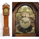A reproduction oak eight day longcase clock with arched brass dial,
