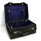 An early 20th century leather gentleman's travel vanity case containing various silver topped glass