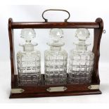 A Victorian oak and silver plate mounted tantalus with three square sectioned decanters, width 35cm.