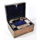 A Victorian rosewood travelling vanity box with brass corner details and part fitted silver plate
