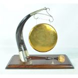 A table top brass gong on cow horn stand with plated mounts on wooden rectangular plinth.