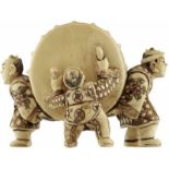 Netsuke FigurengruppeJapan 20. Jh. Elfenbein. Drei Männer mit einer riesigen Taiko-Trommel.