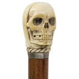 A LATE 19TH/EARLY 20TH CENTURY SUBSTANTIAL WALKING CANE, the pommel carved as a shrouded skull,