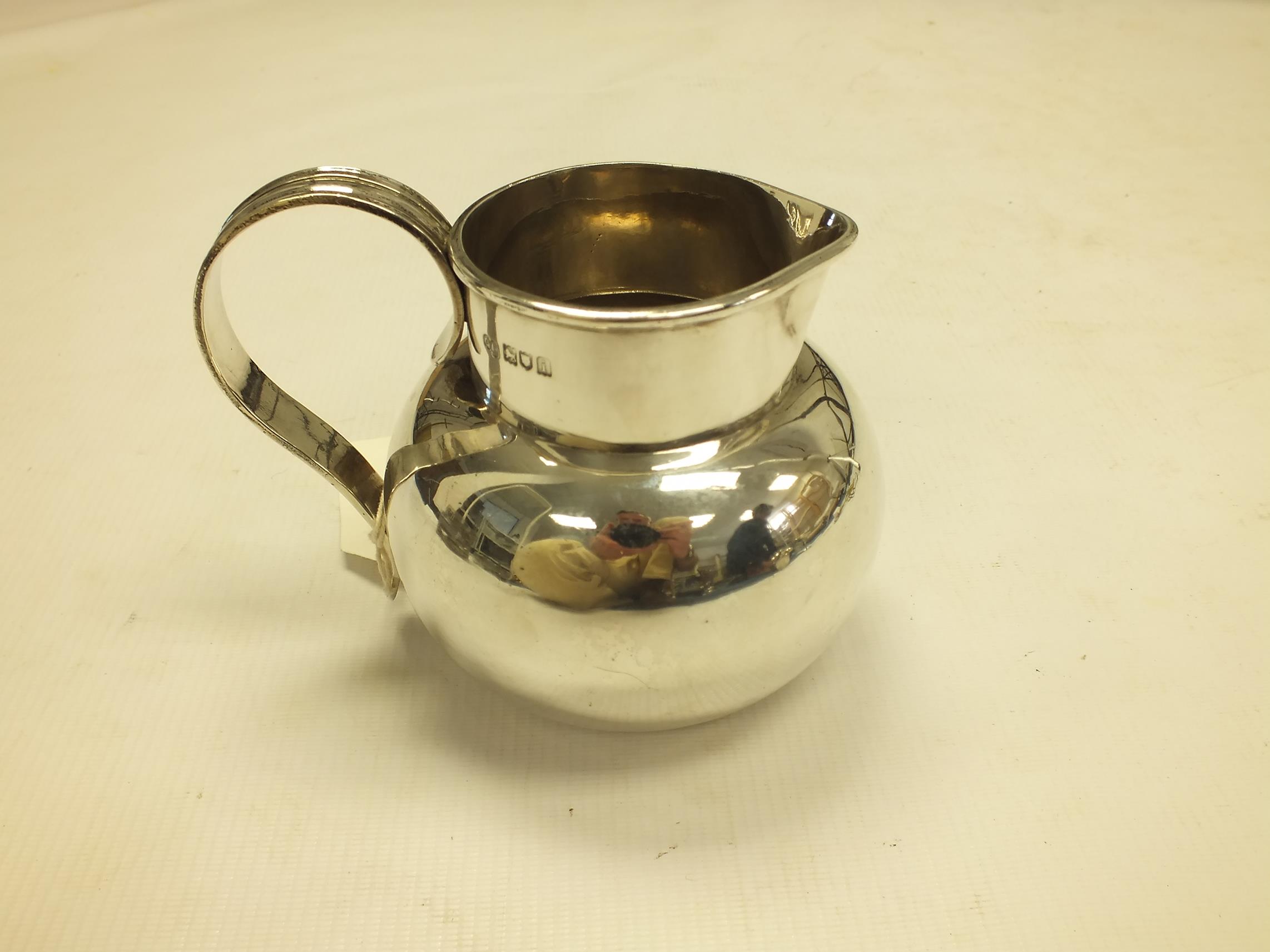 An Edwardian silver jug by George Perkins, London 1904, of plain bulbous form with scroll handle,