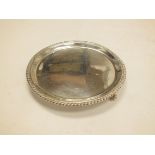 A silver circular tray by Thomas Ducrow, Birmingham 1944, with gadrooned edge and three scroll feet,