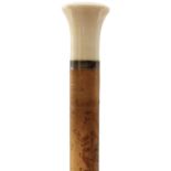 AN EARLY 20TH CENTURY WALKING CANE, the ivory pommel of flattened plain form, above white metal