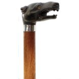 A WALKING CANE WITH CARVED HORN DOG'S HEAD HANDLE, the head inset with green eyes, above silver