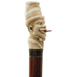 AN EARLY 20TH CENTURY WALKING CANE, the pommel carved as the head of an African gentleman with red