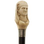 AN EARLY 20TH CENTURY WALKING CANE, the ivory pommel carved as the head of an Egyptian lady, above