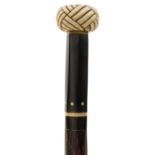 AN EARLY 20TH CENTURY WALKING CANE, the marine ivory pommel carved as a knot and inset with abalone,