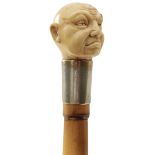 AN EARLY 20TH CENTURY WALKING CANE, the ivory pommel carved as the head of a man, above silver