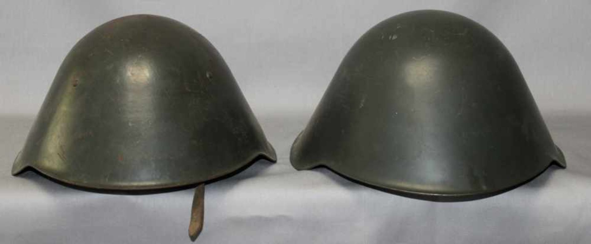 Militaria. Stahlhelm. DDR - NVA.Zwei Stahlhelme der NVA, komplett mit Futter und Beriemung. Aus