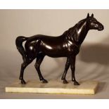 Bronze sculpture of a standing horse looking to the side, on white marble base; bronze cast with