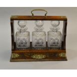 A three bottled oak tantalus with decorated nickel mounts