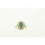 An 18ct H/M emerald & diamond cluster ring, the oval central set emerald approx 1.