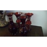 A pair of ruby vases with acid etched decoration of vines and two others, one decorated with a stags