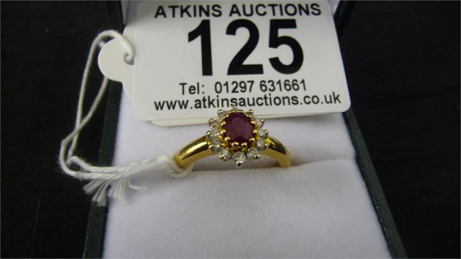 A ruby and diamond cluster ring set in 18ct gold