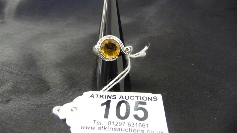 A 9 ct white gold dress ring set with a central yellow stone, with illusion set diamonds surrounding