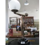 An Art Deco style lamp in the form of a nude lady holding a globe