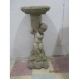 A concrete bird bath, the base formed as a cherub holding an urn