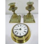 A pair of brass candlesticks along with a brass ship's style clock