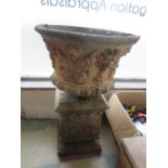 An ornate concrete garden pot on plinth