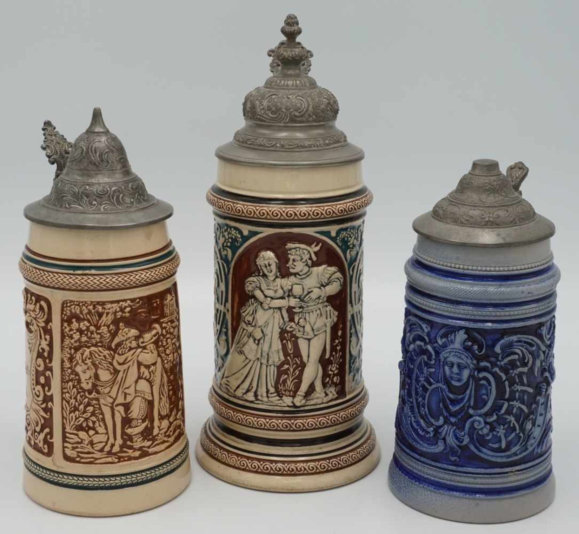 Drei Bierkrüge, um 1900Historismus, braunes und blaues Reliefdekor, Figurenstaffage und