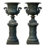 A pair of green lacquered cast iron garden vases in the Medici manner, on accompanying pedestals,