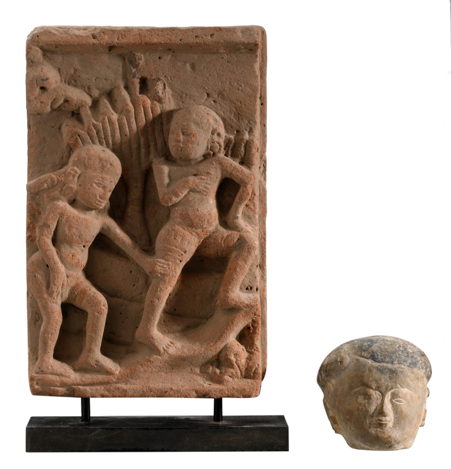 A Burmese stone bas-relief depicting two figures in a garden, on a stand; added an Oriental