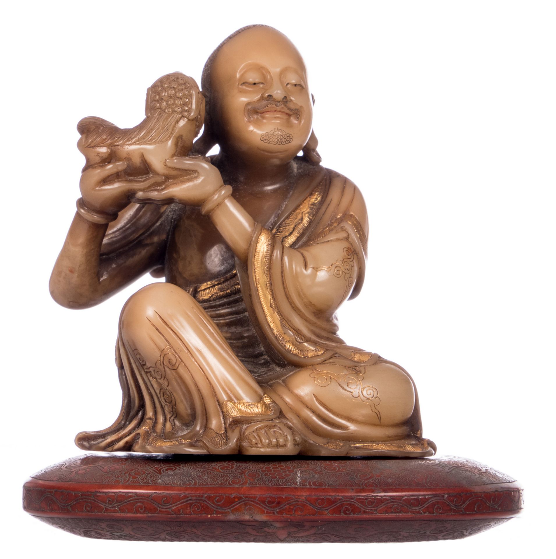 A Chinese gilt and polychrome decorated Shoushan stone Lohan Buddha, on a matching stone cushion,