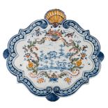 A Dutch Delftware polychrome decorated rococo plaque, the roundel painted with a rural view, (