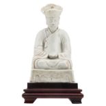 A Chinese blanc de chine figure depicting a seated monk, on a matching wooden base, 18thC, H 20,5 (