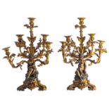 A pair of late 19thC French Rococo style bronze candelabras depicting a children's couple sitting on