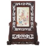 A Chinese carved wooden table screen, the plaque famille rose decorated with an animated scene,