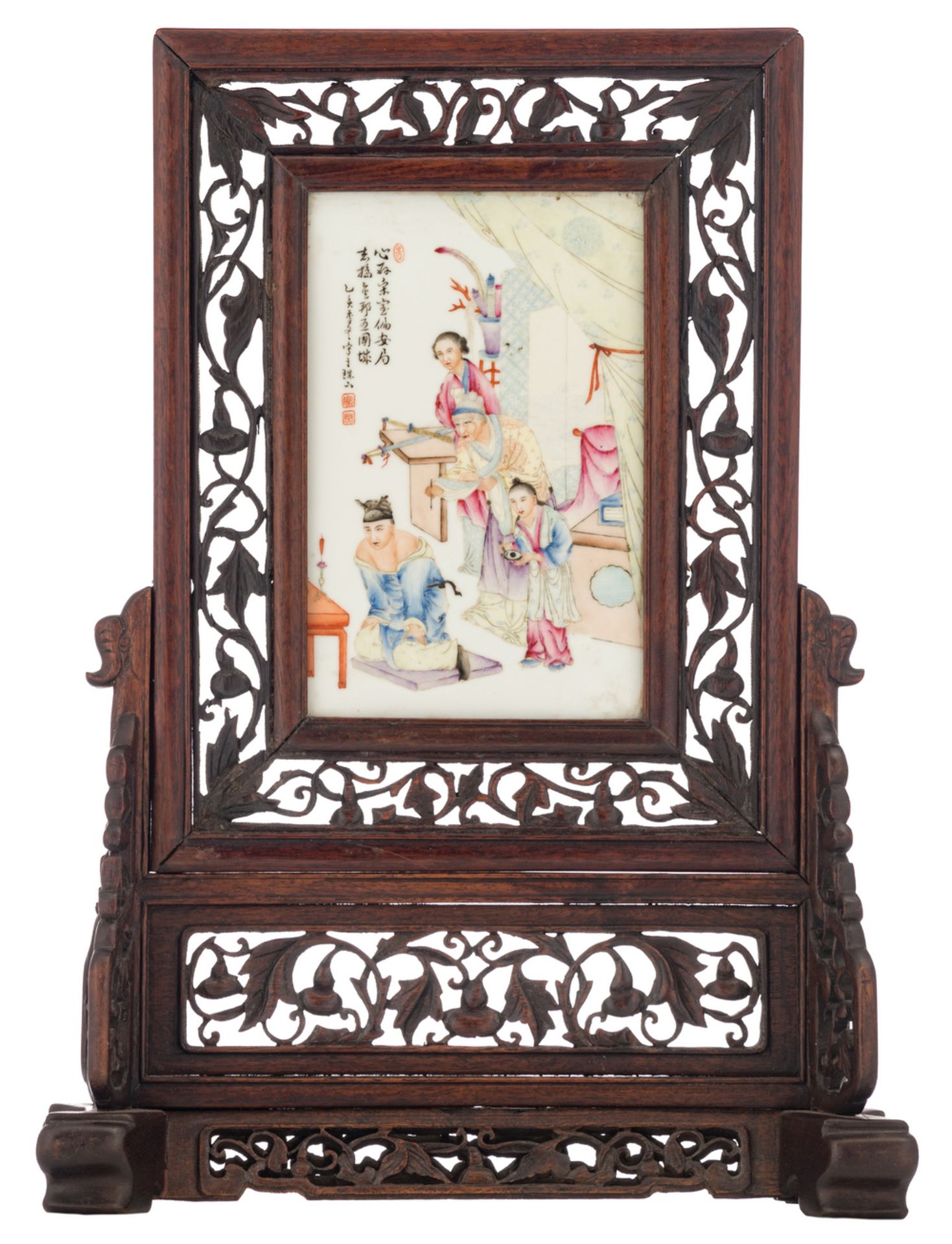 A Chinese carved wooden table screen, the plaque famille rose decorated with an animated scene,