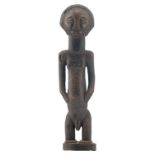 An African wooden sculpture depicting a standing male figure, possibly a chief or an ancestor (