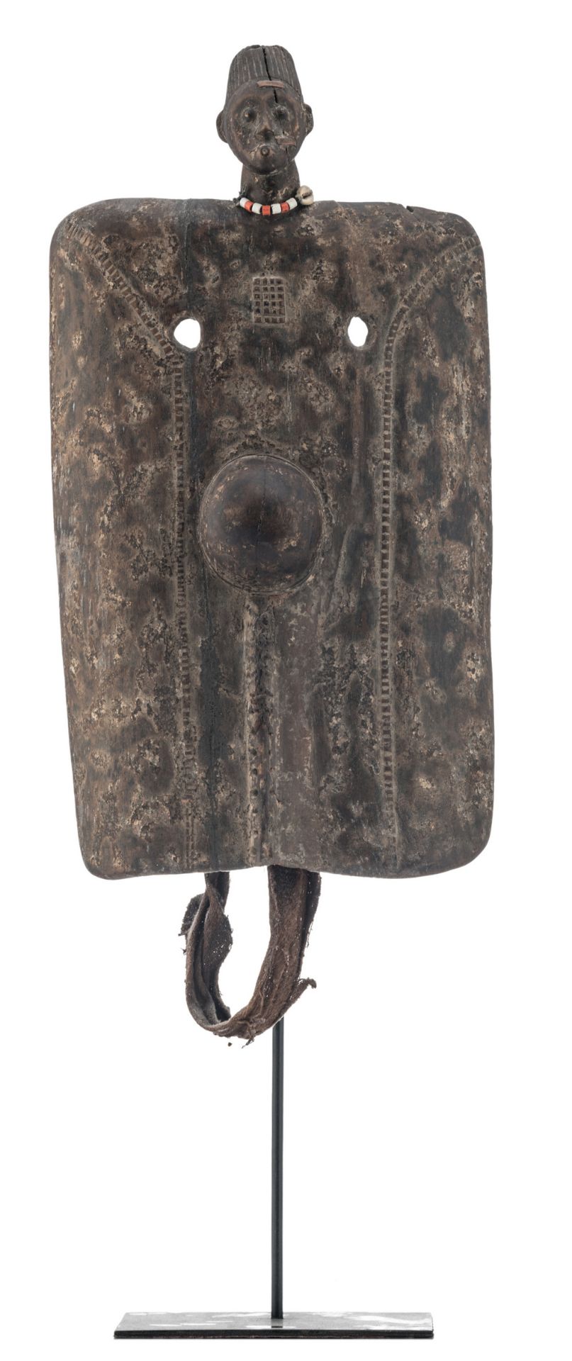 A traditional African wooden shield with on top the head of a man with a beads necklace,